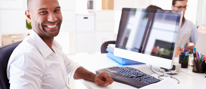 Man in white shirt smiling and using a computer to register for ABCO courses
